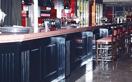 Routed painted panels with granite tops on bar and DJ booth and open shelving for bottle storage.